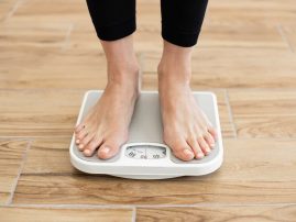 Person standing on scale checking body weight in gym Person standing on scale checking body weight in gym