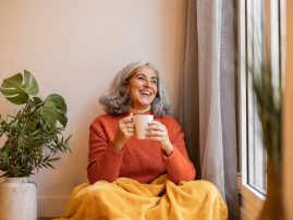 Portrait happy healthy older senior woman sitting at home and drinking coffee. next to the window. Portrait happy healthy older senior woman sitting at home and drinking coffee. next to the window.